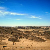 青空が広がる広大な荒野と岩肌の大地、丘陵地帯の風景の写真