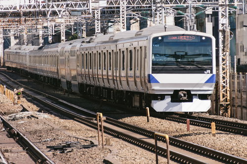 上野東京ラインの通勤型車両が停止する駅の風景