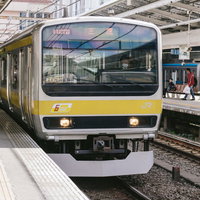 駅のホームに到着する黄色い総武線の電車が停車している風景の写真