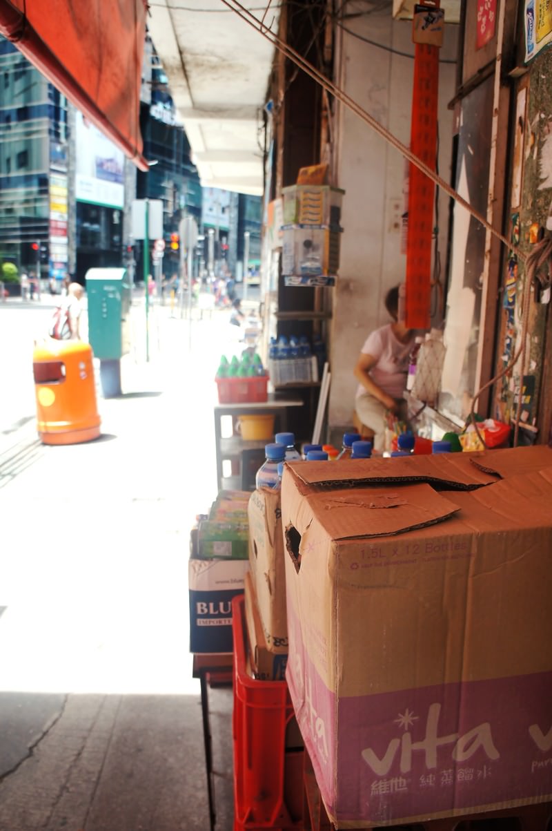 香港の商店街の路地裏に積まれたダンボール箱と奥に見える店舗