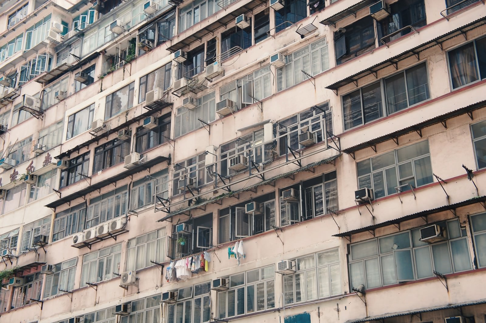 窓と窓型エアコンが密集する古い集合住宅の外壁を見上げた様子