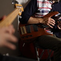 ベースの音合わせをするミュージシャンの手元と指の動きの写真