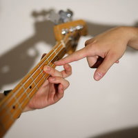 ベースの弦の押さえ方をレクチャーする指先の写真