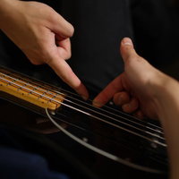 スラップ（プル）のやり方を指導中のベーシストの写真