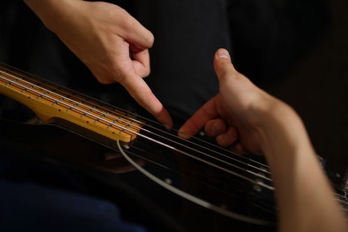 スラップ（プル）のやり方を指導中のベーシスト