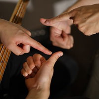 スラップ奏法での親指の位置を確認中のベーシストの写真