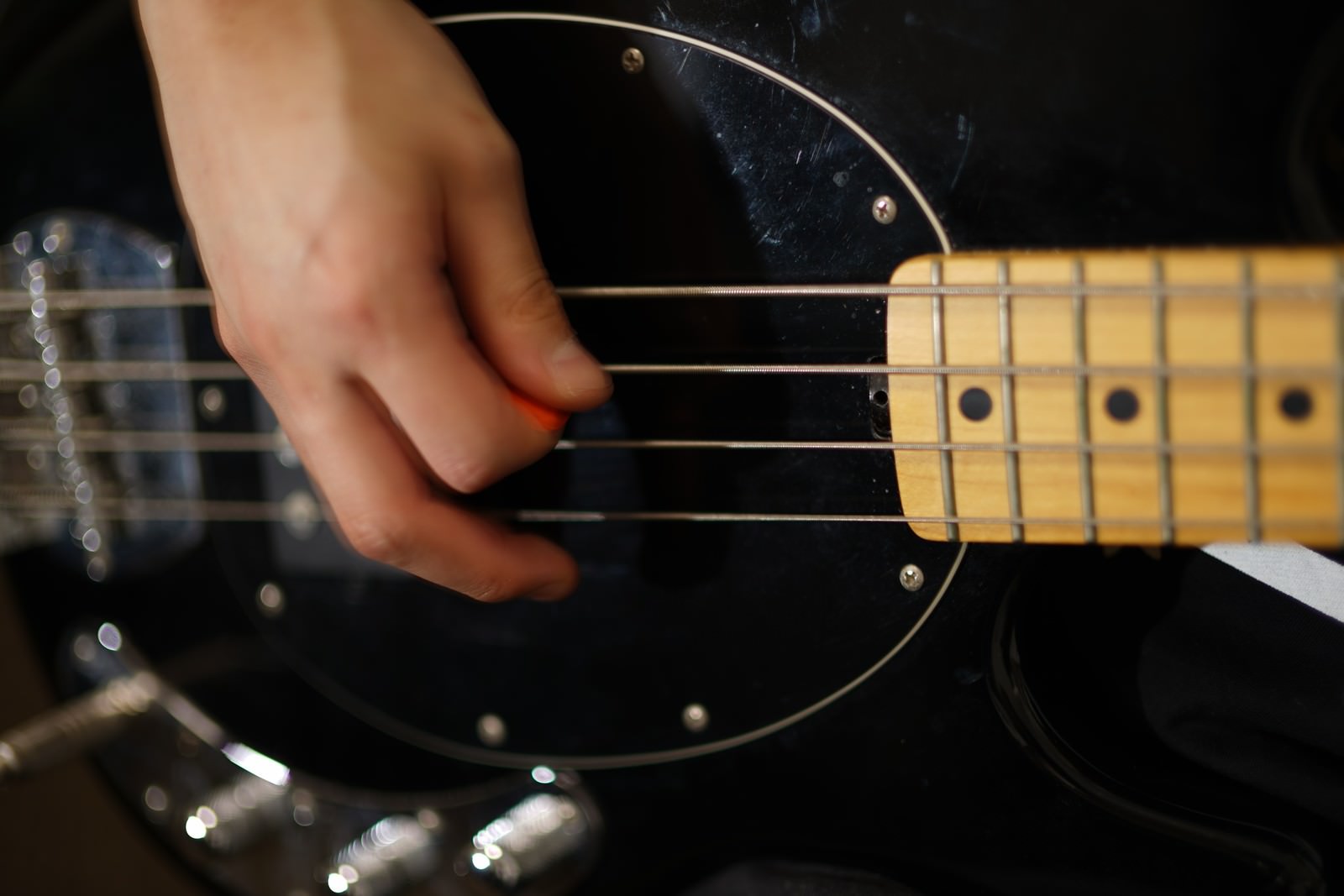 ピックを持った右手で黒いベースギターを演奏している様子