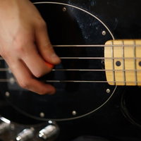 ピック弾きをする右手でベースギターを演奏の写真