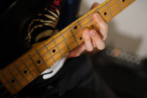 メイプルネックのベースの弦を抑える左手の演奏シーン
