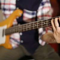 エレキベースの弦を押さえるベーシストの手元の写真