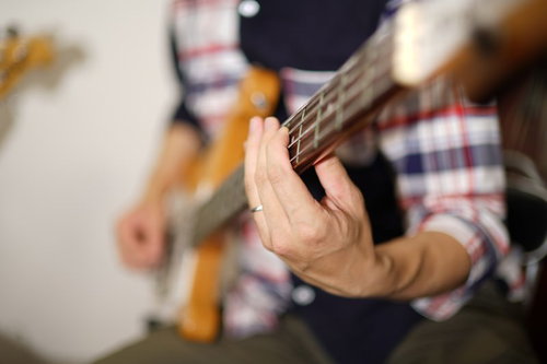 ベーシストの左手元でフレットを押さえる演奏シーン