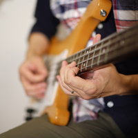 ベースを弾くプロの手元、弦を押さえる指とピックアップの写真