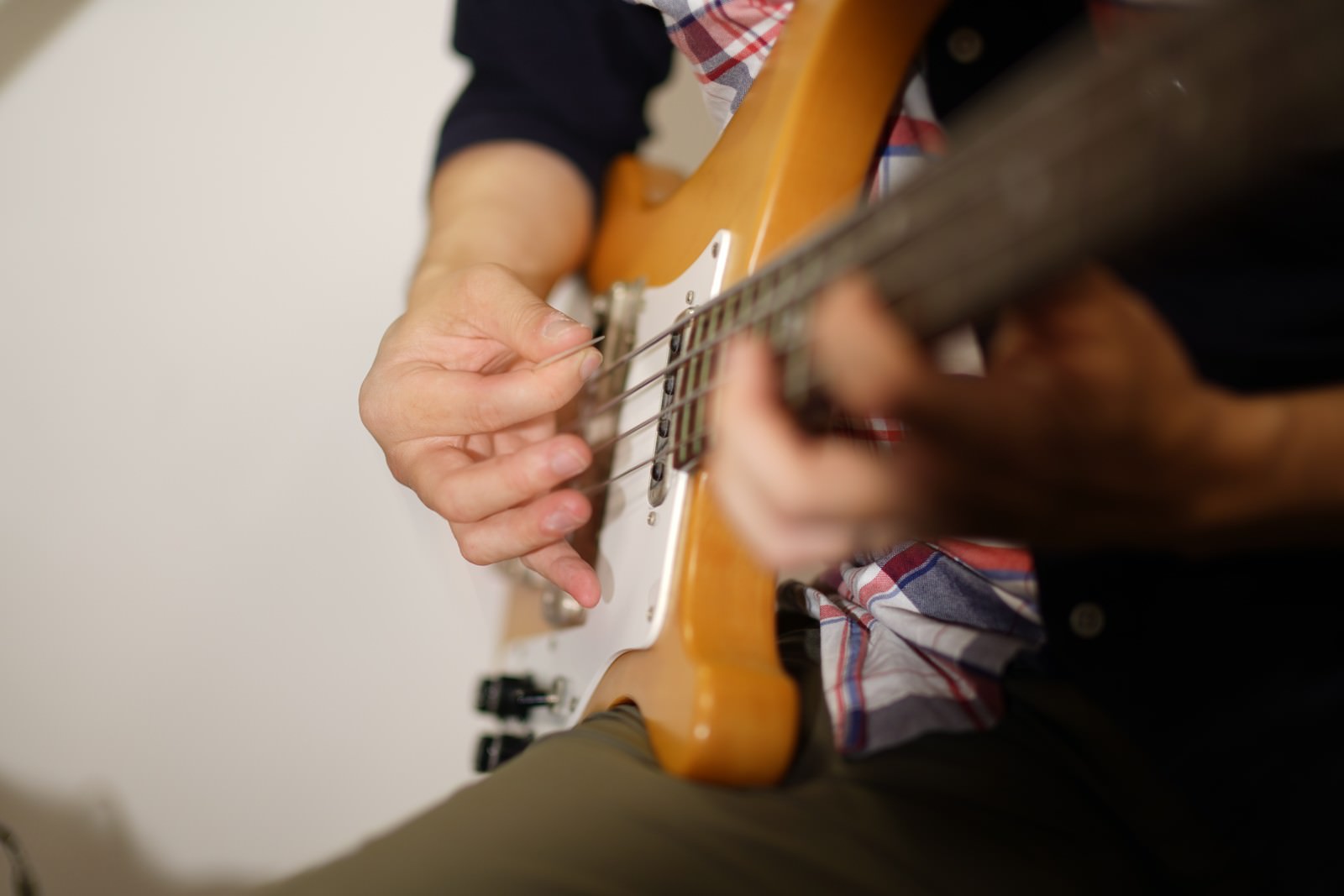ピックを使ってベースを演奏するベーシストの手元