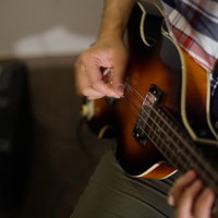 ベースギターを弾くベーシストとアンプの演奏風景の写真