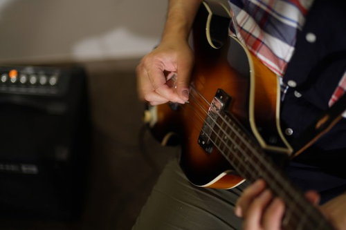 ベースギターを弾くベーシストとアンプの演奏風景