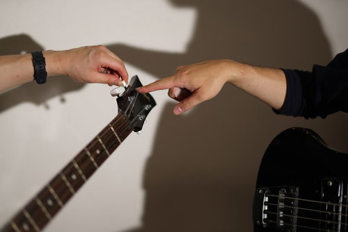 ベースのチューニングのやり方を教わる生徒とベース講師