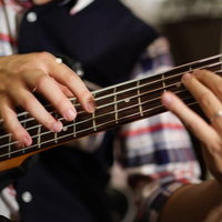 チェック柄シャツのベーシストによるライトハンド奏法の写真