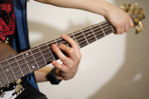 ベースギターをクロスタッピングで演奏するベーシスト
