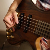 ベースの弦を指弾きするベーシストの右手の演奏風景の写真