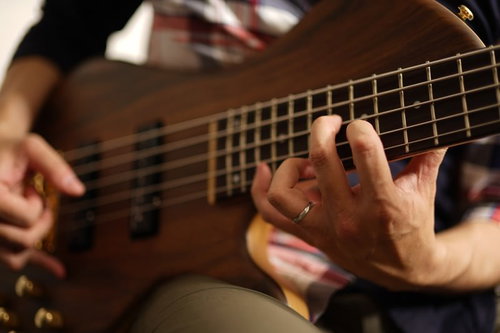 5弦ベースのハイポジションを押さえるベーシストの左手