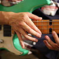 エレキベースのフレットボードをタッピング演奏する手元の写真