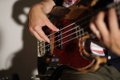 ベーシストが弦を指弾きして演奏する手元の瞬間
