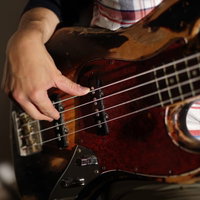プロベーシストが指弾きする茶色いベースの右手の写真