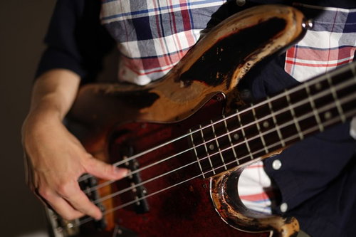 チェック柄シャツを着たベーシストのベース演奏の手元