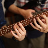 弦の押さえ方のお手本を見せるベース講師の左手の写真