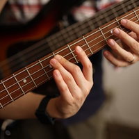 ベースの弦の押さえ方を手を添えて教えてもらうの写真