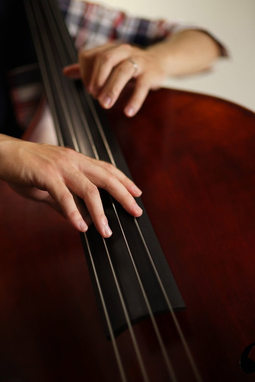 ウッドベースを弾くベーシストの手元をクローズアップ
