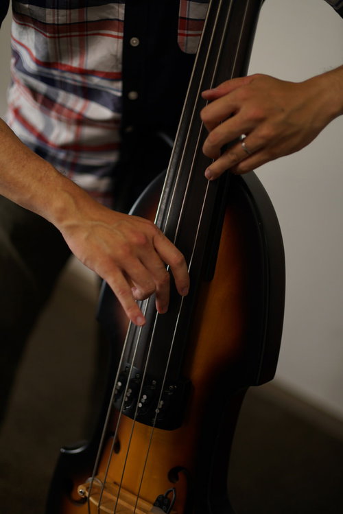 チェック柄のシャツを着たベーシストがウッドベースで演奏