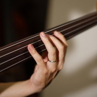 ベースの4弦を押さえるベーシストの左手の運指フォームの写真