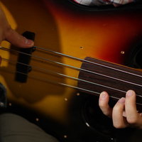 サンバーストカラーのエレキベースを指弾きするベーシストの手元の写真