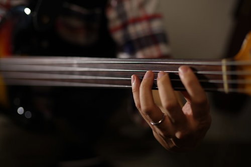 ウッドベースの弦を押さえるミュージシャンの指