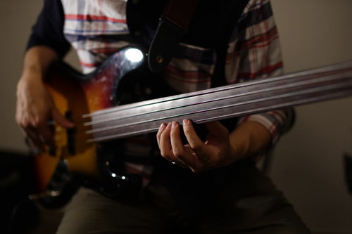 室内でベース練習をするベーシストの手元と全身