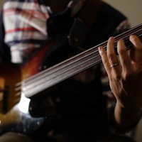 ベーシストの手元でベースを弾く演奏シーンの写真