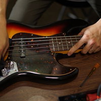 ベースギターを磨いてメンテナンス中のベーシストの写真