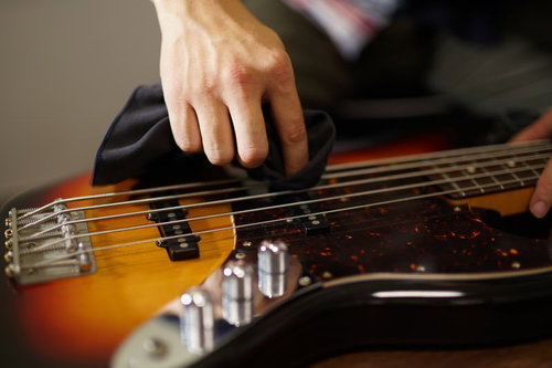 クロスでベースの弦を一本ずつ拭くメンテナンス