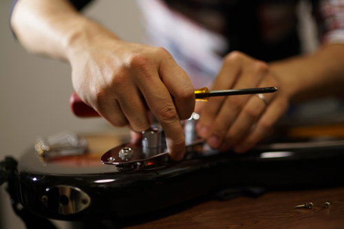 ベースの弦を調整・メンテナンスする手元と工具