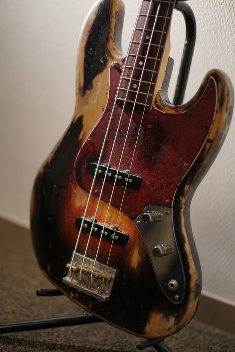 サンバーストカラーの木目が美しいエレキベースが壁際に立てかけられている