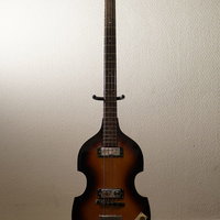 スタンドに置かれた茶色のエレキベース、黒いネック付きの写真