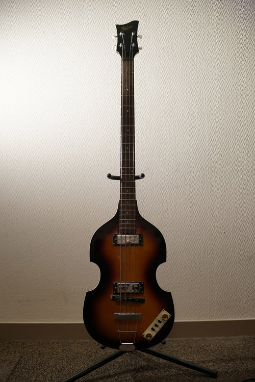 スタンドに置かれた茶色のエレキベース、黒いネック付き