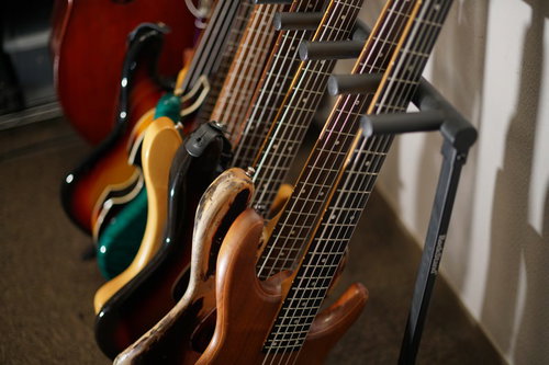 楽器店に並ぶ複数本のエレキベース、赤色と茶色の異なる色合い
