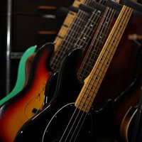 スタンドに整然と並ぶエレキベース群、複数の楽器が展示された様子の写真