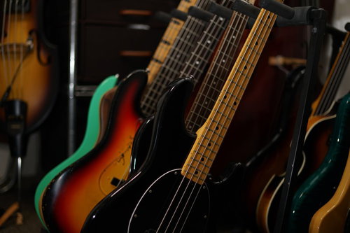 スタンドに整然と並ぶエレキベース群、複数の楽器が展示された様子