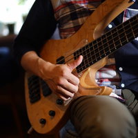 5弦ベースでスラップ奏法を使って弾くベーシストの写真