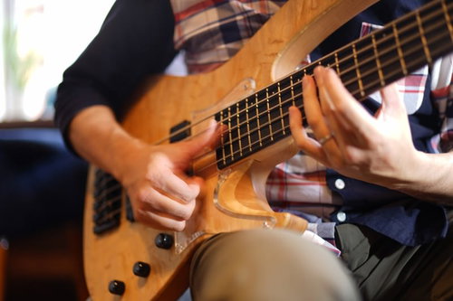5弦ベースでスラップ奏法を演奏するベーシストの手元