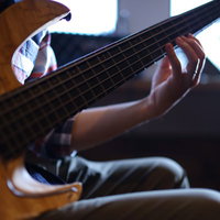 ベースを指弾きする左手の演奏風景とフレットボードの写真