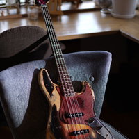 カフェのテーブルに置かれた赤いピックガードのエレキベースの写真